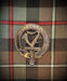 "Ireland" Kilt Pin in bronze colour. Harp in the center of Kilt Pin with Ireland written across the top. Background of weathered mckenzie tartan